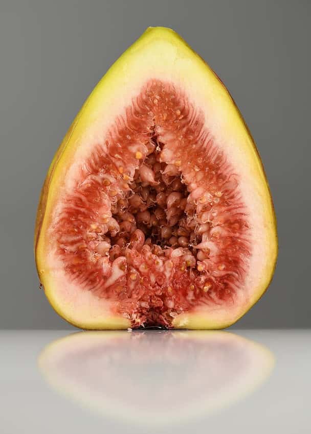 A ripe common fig cut open beside whole fruit.